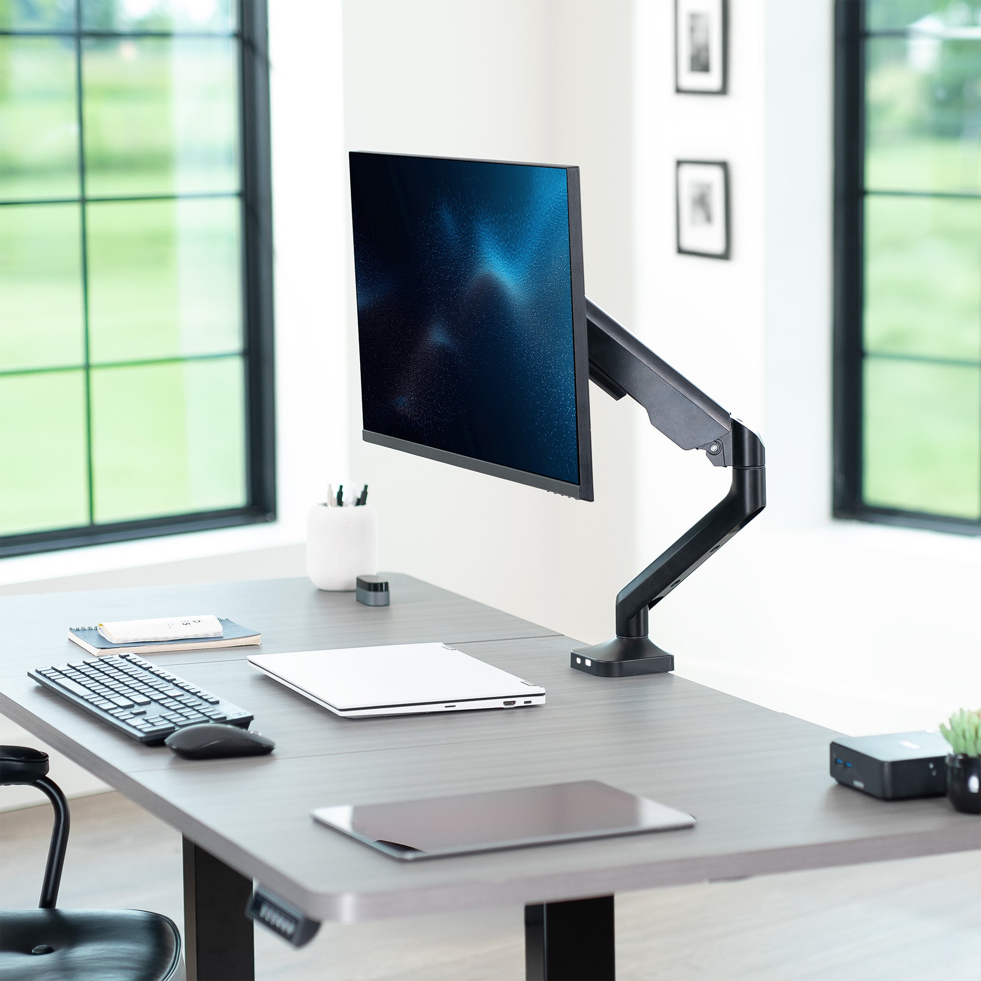 Modern office desk setup with a monitor on a stand, keyboard, and mouse.