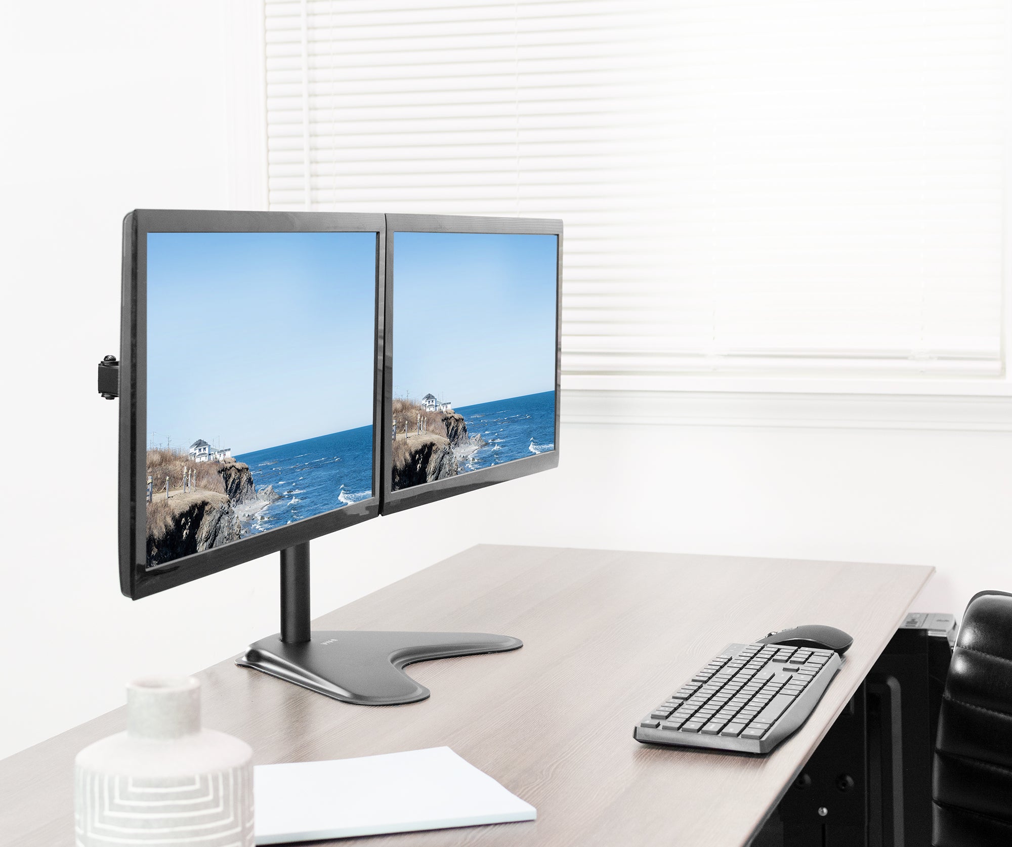 Two computer monitors on a desk with a keyboard and mouse, displaying a scenic view.