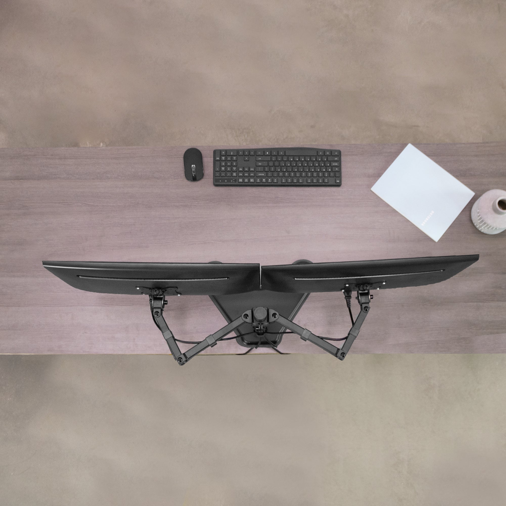 Desk setup with dual monitor, keyboard, mouse, and paper on a wooden desk.