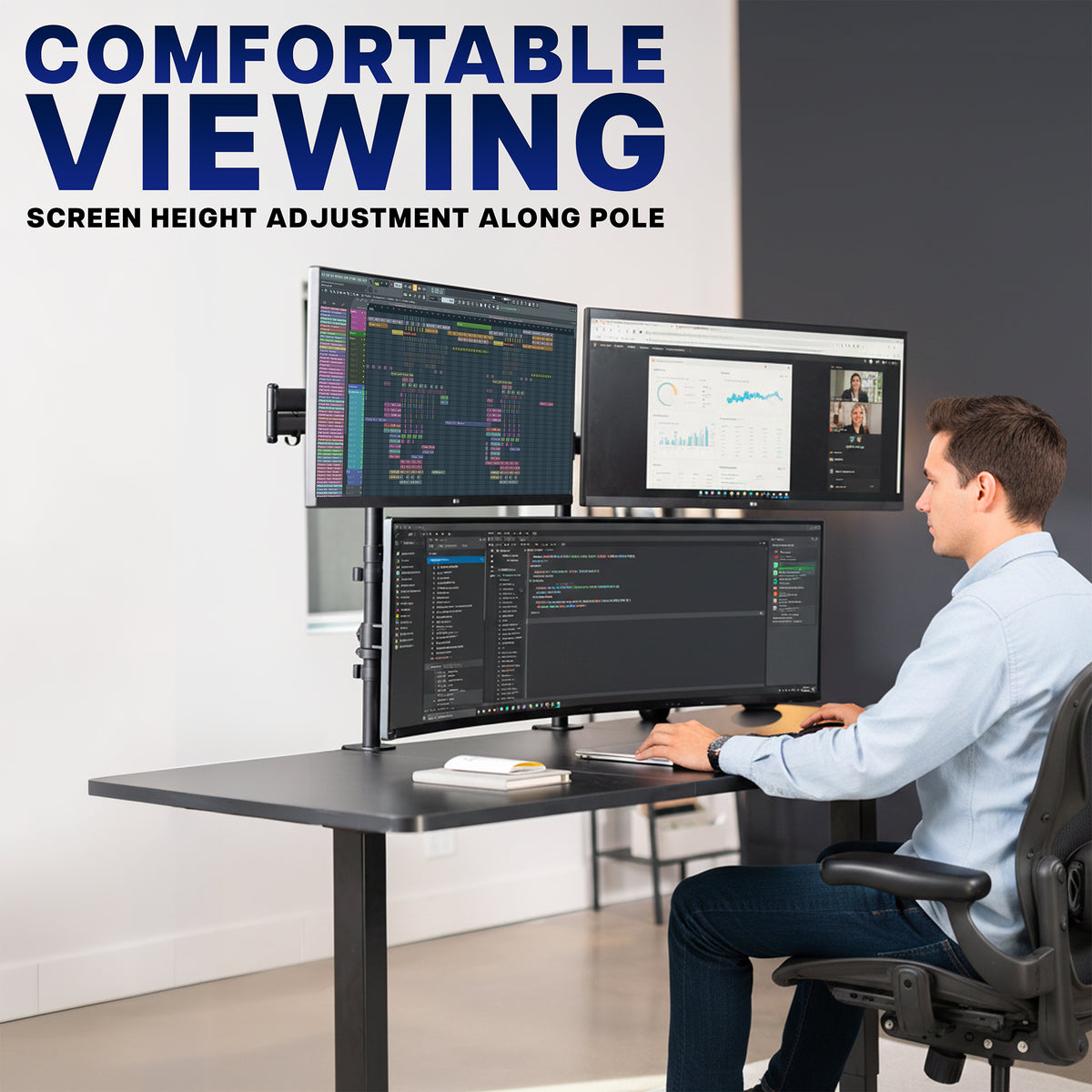 A man sits at a standing desk with three computer monitors mounted on an adjustable desk-mounted pole. Large text in the upper left reads 'COMFORTABLE VIEWING' with smaller text 'SCREEN HEIGHT ADJUSTMENT ALONG POLE.
