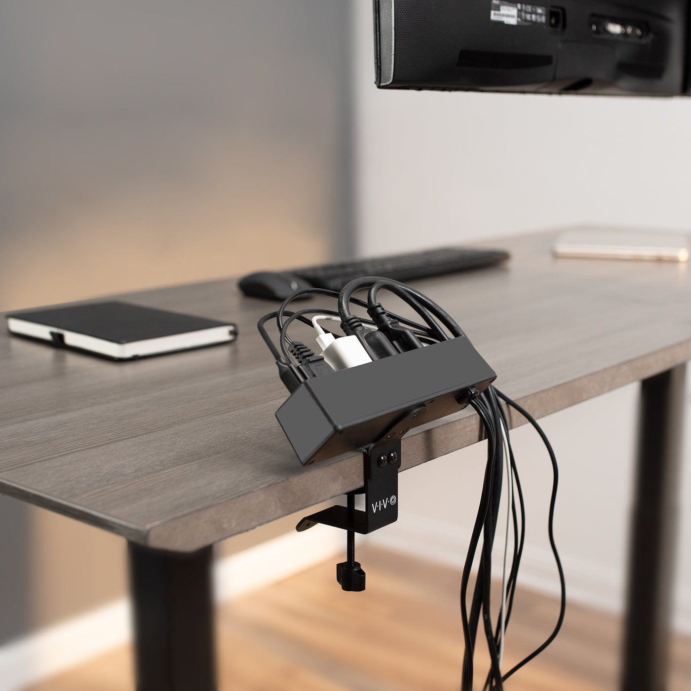 Power strip clamped to the back of a desk for easy cord access and management.
