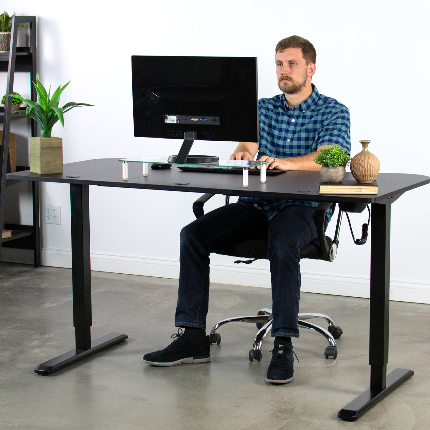 A person working at a sit-to-stand desk in an office. 