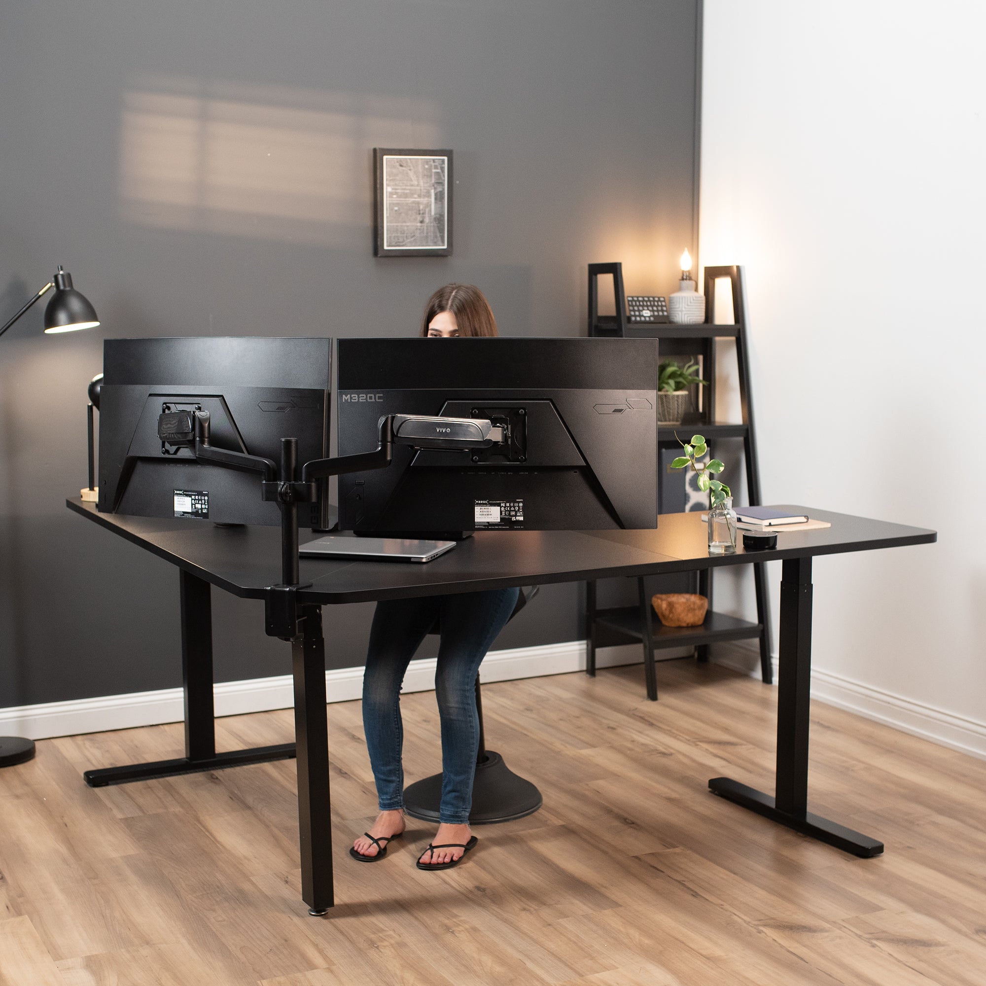 A person working in a modern office setup with a curved L-shaped corner desk.