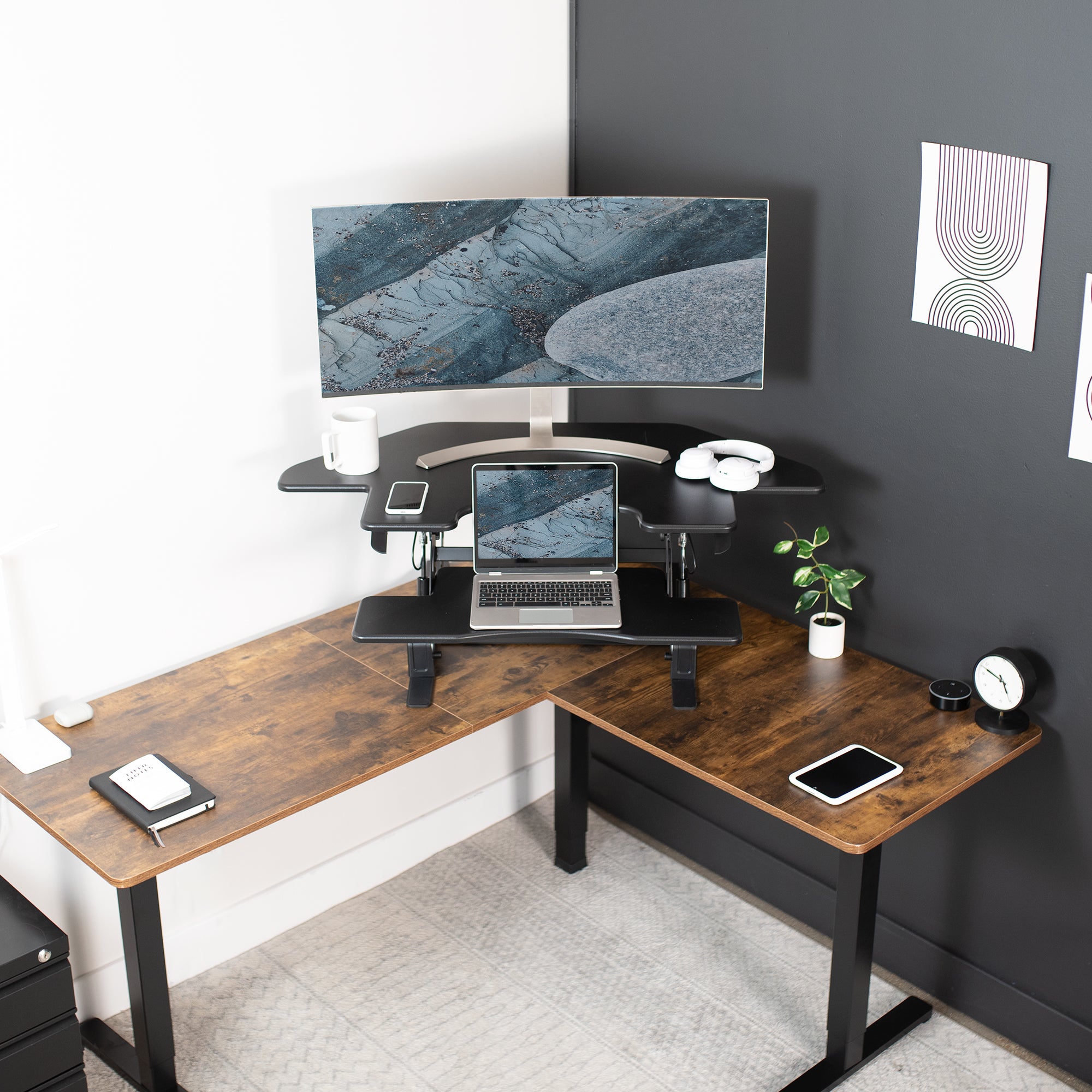 Large curved monitor mounted on top of the two-tier monitor stand with a laptop on the corner desk.