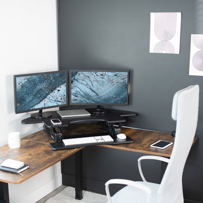 Spacious corner desk converter with keyboard, mouse, monitors, laptop, and other office equipment.