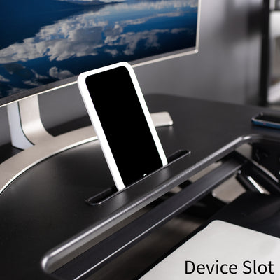 Designated device slot located center front on the top layer of desk riser.