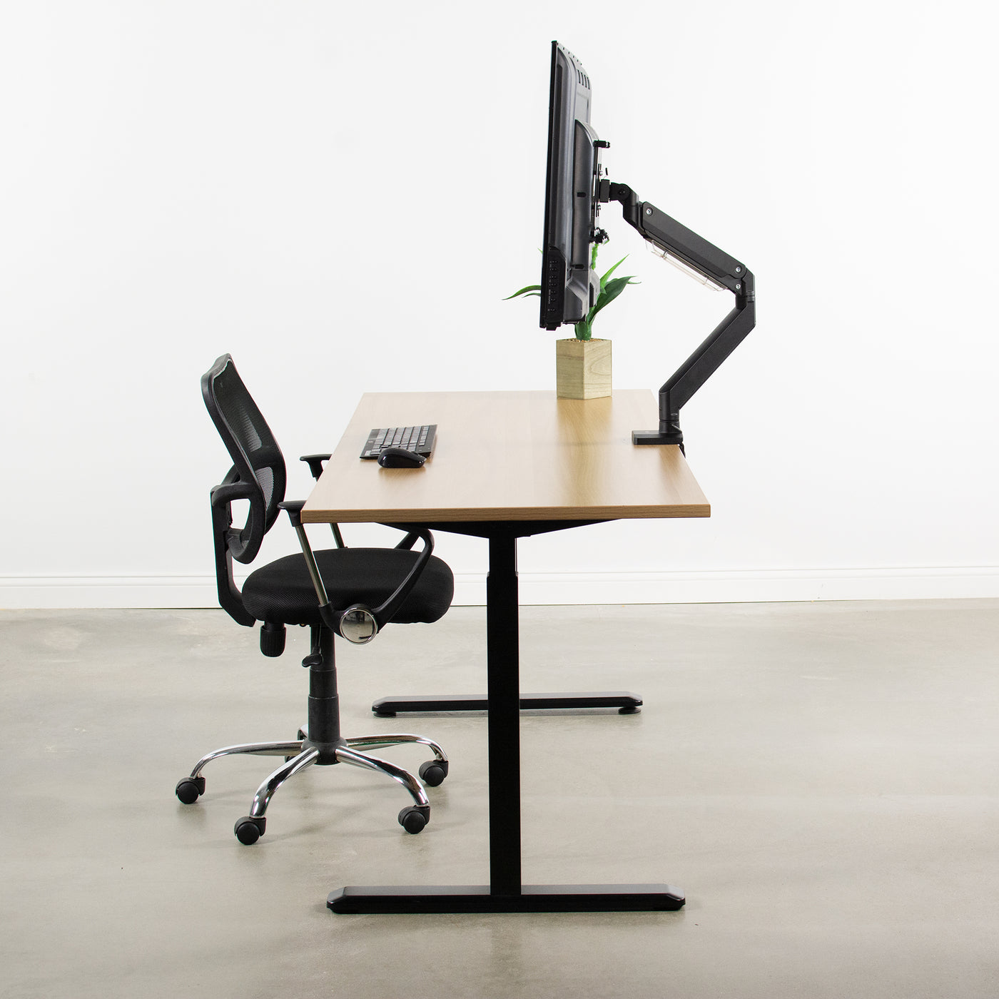 Side view of modern office desk space with large desk-mounted monitor, pneumatic arm, and sturdy VESA plate.