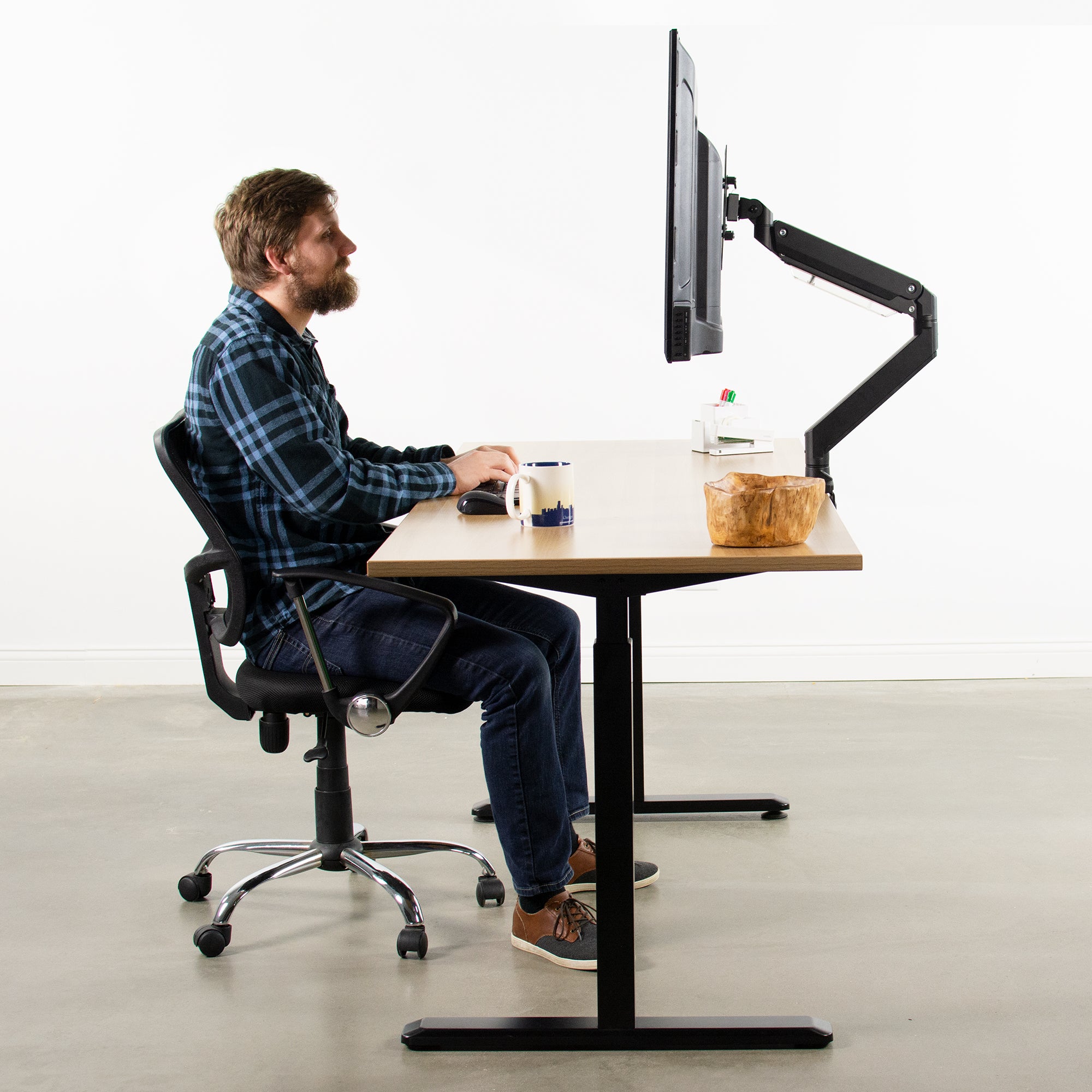 A man working at a desk with a large tv monitor and sturdy VESA plate.