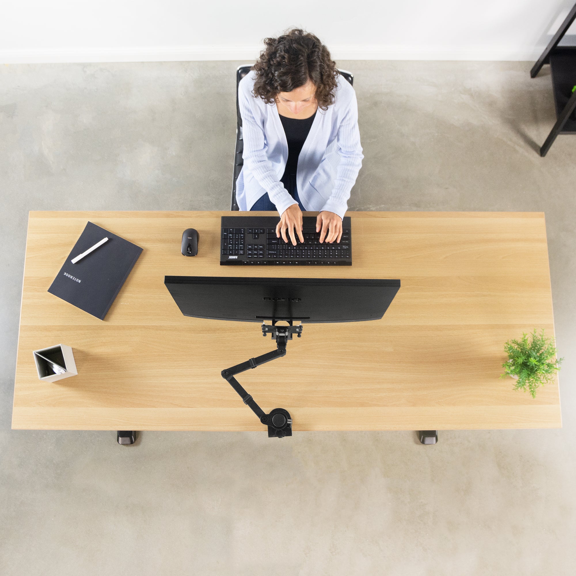 Ergonomic office set up with a woman working from a desk with a mounted BenQ monitor supported by a mount and VESA plate adapter bracket.