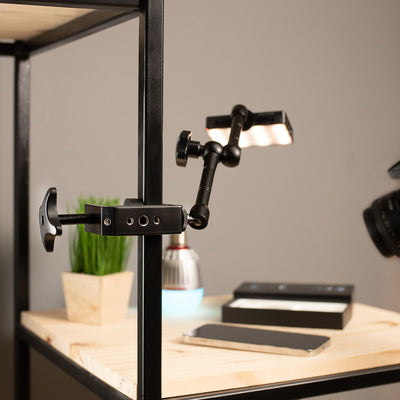 A desk mount clamp attached to a clamp on a desk shelf.
