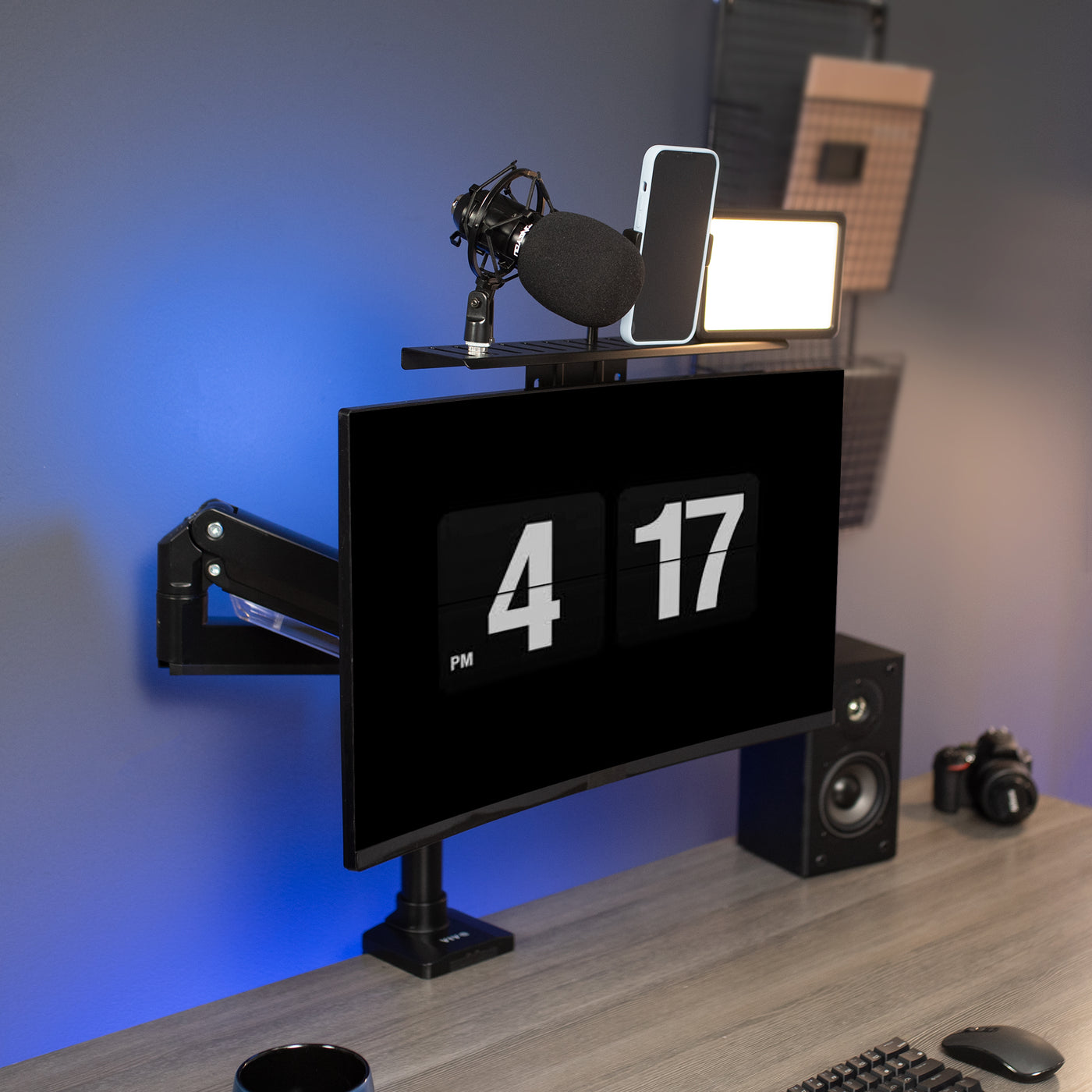 Live stream accessory shelf with a microphone and phone mount in a studio office.