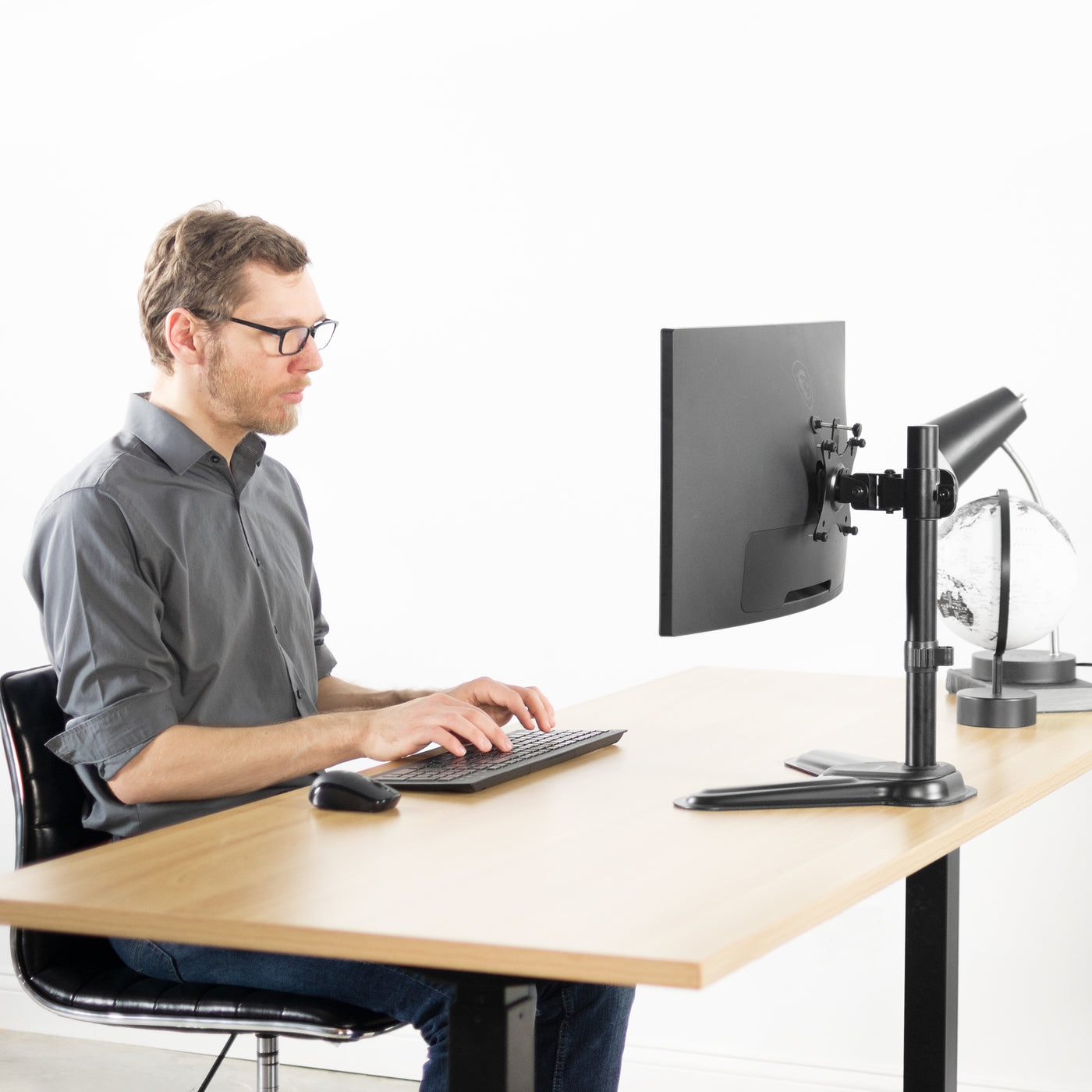 A person working at an ergonomic desk with a mounted Viotek monitor screen.