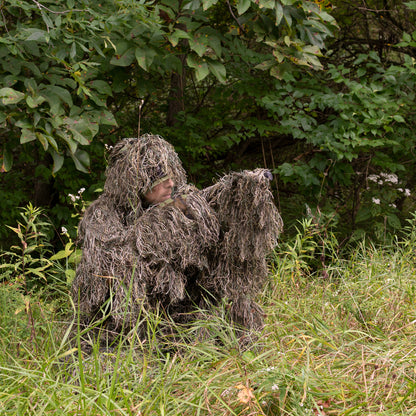 Man in a ghillie suit blending into the outdoor environment.