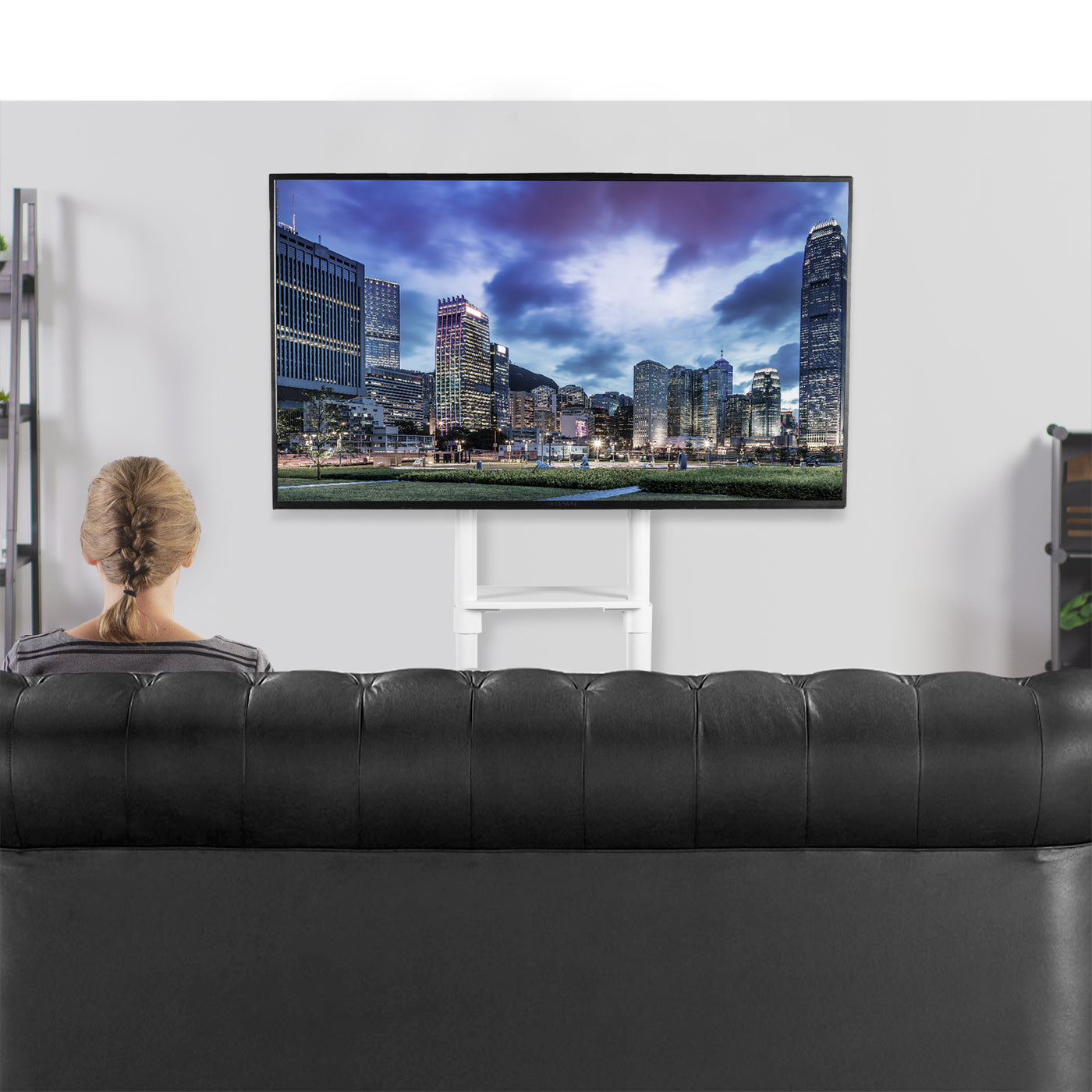 Large TV screen mounted to a mobile TV stand with locking caster wheels.