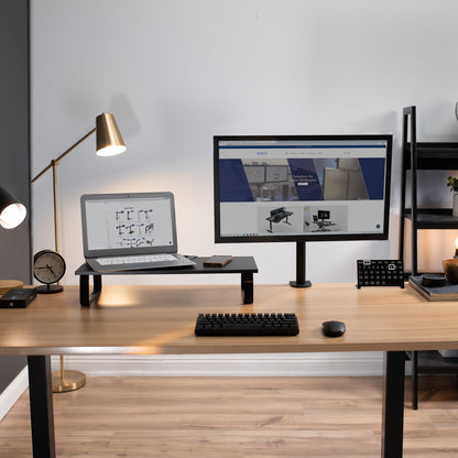 Top of desk riser elevating a laptop and phone a couple of inches higher than the main desktop with a clap on monitor mount beside.